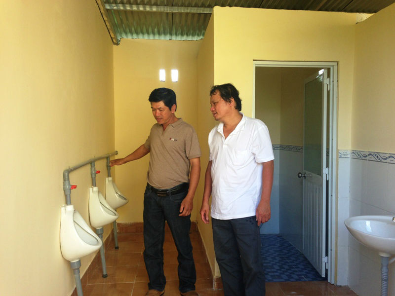 Bác sĩ Trương Hữu Khanh (phải) và ông Chu Đức Hùng (trái) bên cạnh nhà vệ sinh mới xây cho học sinh tiểu học ở Lâm Đồng.