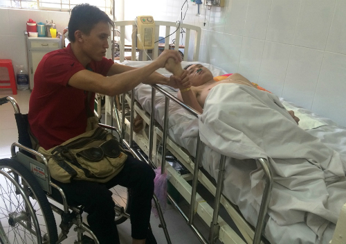 Đức ngồi xe lăn chăm sóc Linh ở bệnh viện. Ảnh: Lê Phương.